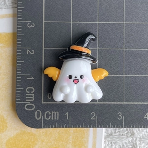 Macro view of cartoon ghost resin charm with wizard hat and wings on scale mat
