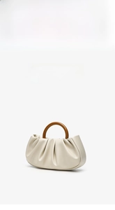 Close-up of pleated cloud clutch bag with brown circular wooden handle detail