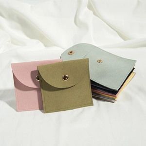 Macro detail of microfiber jewelry envelopes with snap buttons on white silk background