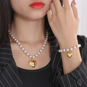 Parure collier et bracelet en perles vintage avec pendentifs cœurs dorés sur mannequin