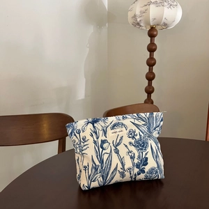 Close-up of floral fabric makeup bag with simple wish label on vintage wood table