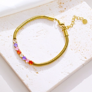 Golden snake chain bracelet with colorful zircons on white stone base display