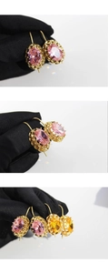 Detail of oval gemstone earrings with vintage gold base in pink and amber colors