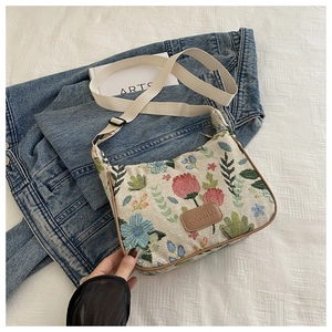 Close-up of floral jacquard fabric with leather logo and adjustable shoulder strap