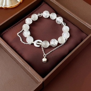 Detail of beaded bracelet with white cat's eye, crystal moon charm, and bell in a gift box