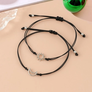 Detail of adjustable sun and moon braided bracelets with silver pendants on black wax cord