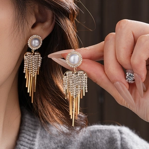 Detail of long tassel earrings with sparkling cubic zirconia and white pearls on a model