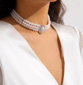 Close-up of triple-layer pearl choker with a sparkling oval crystal pendant detail