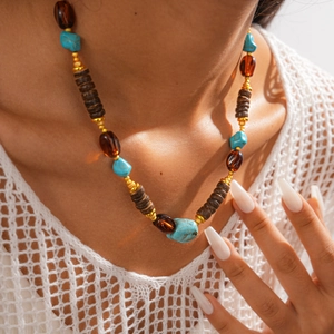 Detail of bohemian sweater chain with turquoise, amber beads and golden spacers