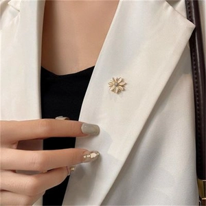 Elegant champagne gold flower brooch pinned on a white blazer lapel for detail