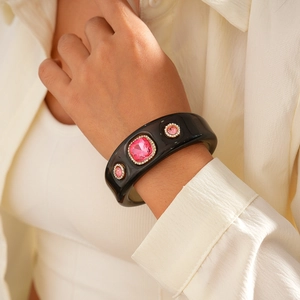 Detail of vintage black resin bangle with pink square gemstone and white rhinestones
