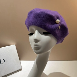 Detail view of purple wool beret with large decorative pearl and gold accent piece