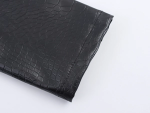 Close-up of black PU leather coat with realistic embossed crocodile skin texture