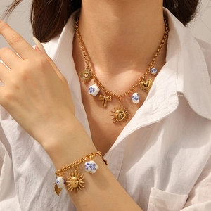 Detail of gold chain set with sun face, heart charms and blue floral ceramic beads