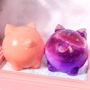 Detailed view of pink and glittery purple pig resin figurines with curly tail details
