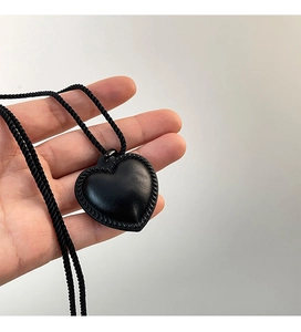 Détail du pendentif cœur en cuir noir avec texture tressée et cordon assorti