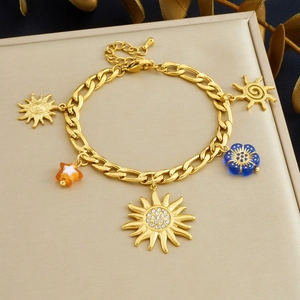 Detailed close-up of a gold-plated sun and star pendant bracelet on a beige jewelry box