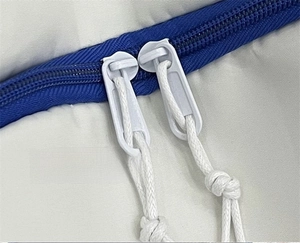 Detail of durable double zipper with white woven cord pulls on a large capacity backpack