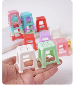 Miniature dollhouse plastic stools in various candy colors shown for scale in hand