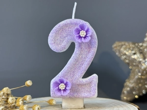 Detailed view of number 2 purple glitter birthday candle with delicate floral accents