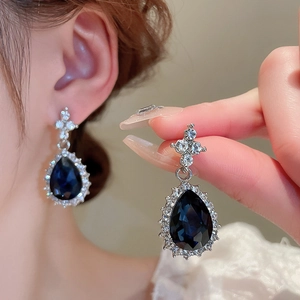 Detail of blue teardrop crystal earrings with silver setting and small rhinestones