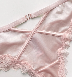 Detail of pink satin thong with delicate lace trim and heart-shaped metal buckle