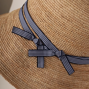 Women straw sun hat with blue striped bow detail for beach and summer travel protection