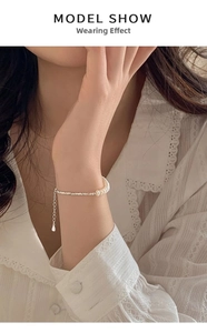 Detail of freshwater pearl and silver bead bracelet on woman wrist with lace collar