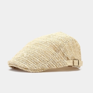 Detailed close-up of beige straw flat cap showing woven texture and adjustable metal buckle
