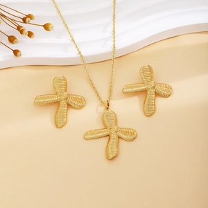 Golden knot bow necklace and earrings set displayed on elegant textured wave surfaces