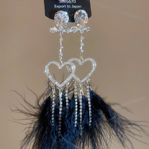 Detail shot of elegant heart-shaped earrings with long black feathers and crystals