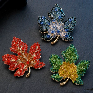 Elegant maple leaf brooch pins with vibrant gradient rhinestones on black rock background
