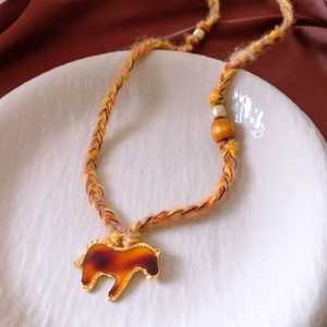 Detail of horse resin pendant on orange woven cord with wooden beads necklace