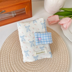 Detail of floral fabric book cover with blue bow, pink heart button and woven label