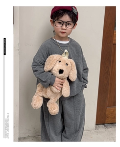 Detail view of a cute plush dog backpack styled with a dark grey toddler tracksuit