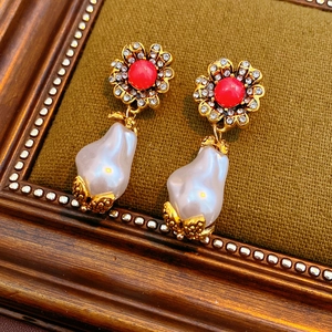 Macro shot of vintage gold flower earrings with coral beads and baroque pearls