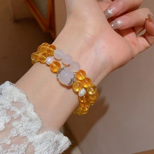 Macro detail of layered white chalcedony and yellow crystal beaded bracelets on wrist
