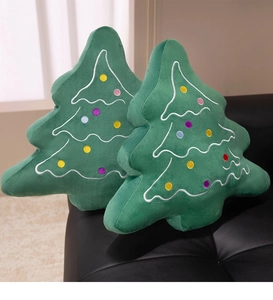 Detailed view of plush Christmas tree pillows with wave embroidery on a black leather sofa