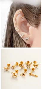 Macro detail of gold-tone stainless steel cartilage studs with zircon butterfly and spider