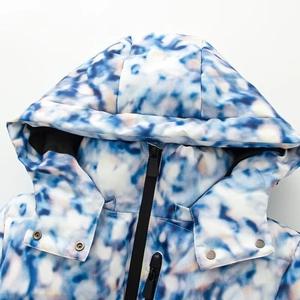 Close-up of hooded collar with metal snap buttons and blue tie-dye texture on ski jacket