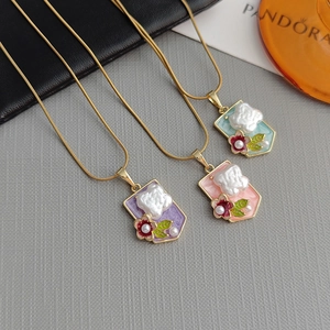 Three elegant flower shield necklaces with colorful enamel and pearl in a 45-degree view