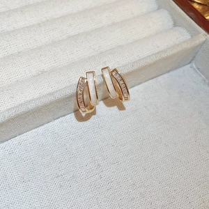Macro shot of gold plated C-shaped earrings with shell inlay and cubic zirconia details