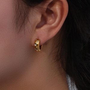 Boucles d'oreilles créoles dorées épaisses avec pavé de cristaux brillants sur modèle