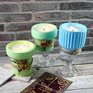 Three colorful succulent-shaped candles in ceramic pots on glass pedestals for decor