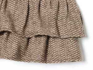 Dettaglio della trama in tweed marrone a spina di pesce e dell'orlo della gonna