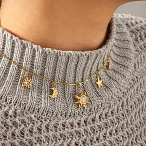 Collier céleste doré avec pendentifs soleil lune et étoile sur pull en maille