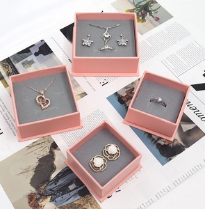 Detailed top view of pink jewelry gift boxes with grey velvet lining and assorted accessories