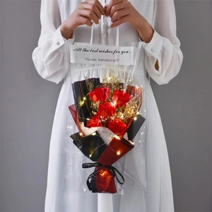 Detailed view of artificial red rose bouquet with LED string lights in clear gift bag
