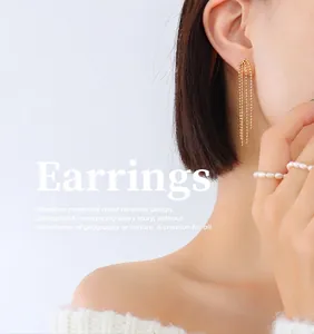 Élégantes boucles d'oreilles longues à pompon plaqué or 18 carats portées sur modèle