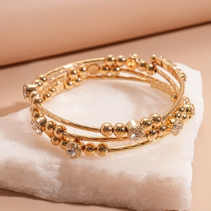 Detail of multi-layer gold beaded bracelet with sparkling rhinestones on stone stand